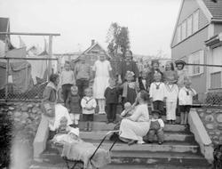 Barna på kvartal y i trappa. To kvinner og atten barn. Hus i