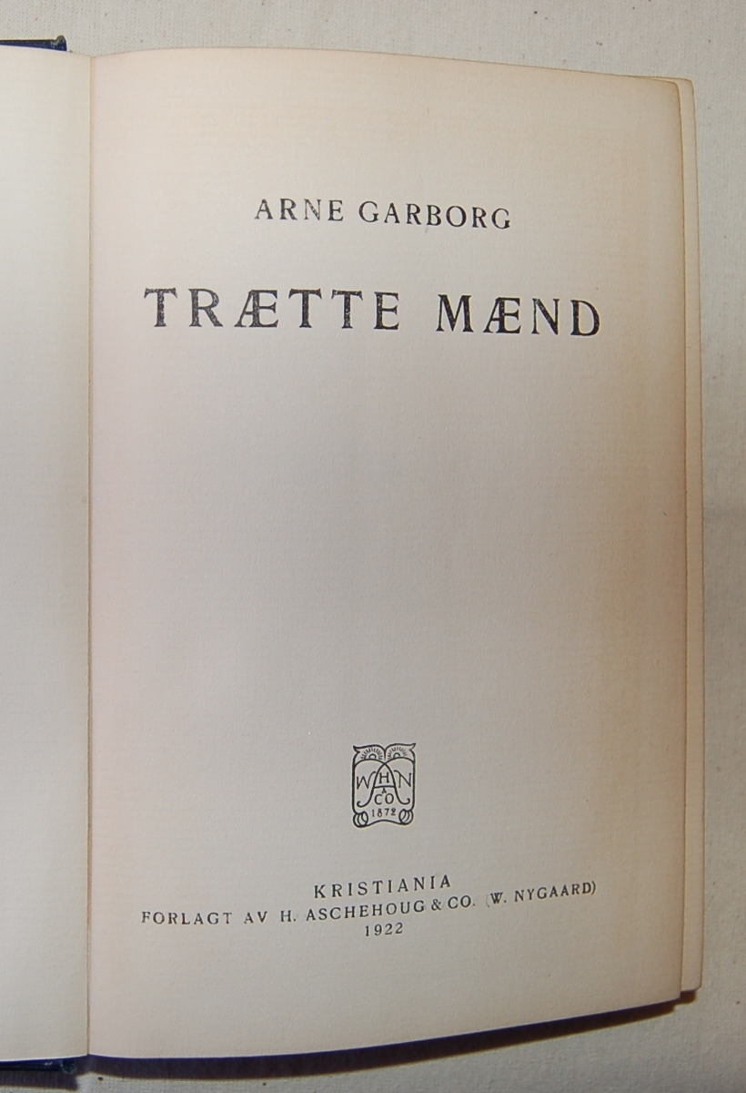 På bokens forside: Stiliserte bokstaver i gull på blå bakgrunn