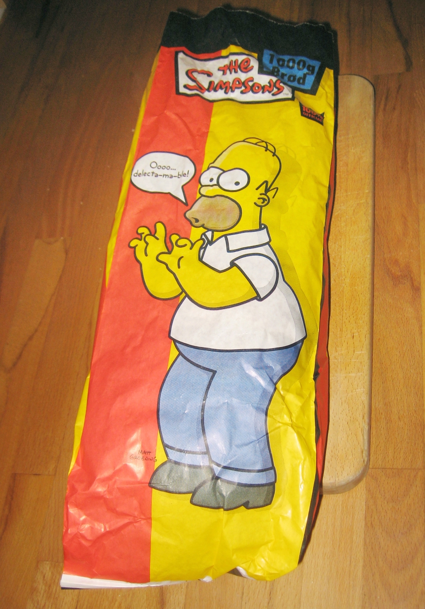 Forsiden: Motiv er tegneseriefiguren Homer Simpson fra the Simpsons. Han står og sier (i en tegneserieboble) "Oooo...delecta-ma-ble! Baksiden: Hele Simpson-familien + hund og katt.