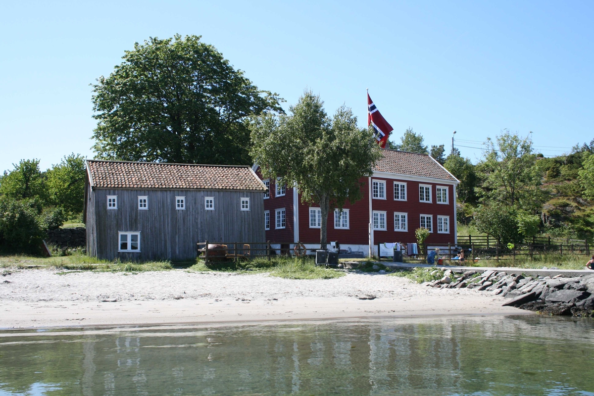 Merdøgaard, gårdstun, sett fra N, fra sjøen, sjøbod og våningshus. Tunntreet, lønn, synlig over sjøboden. 
