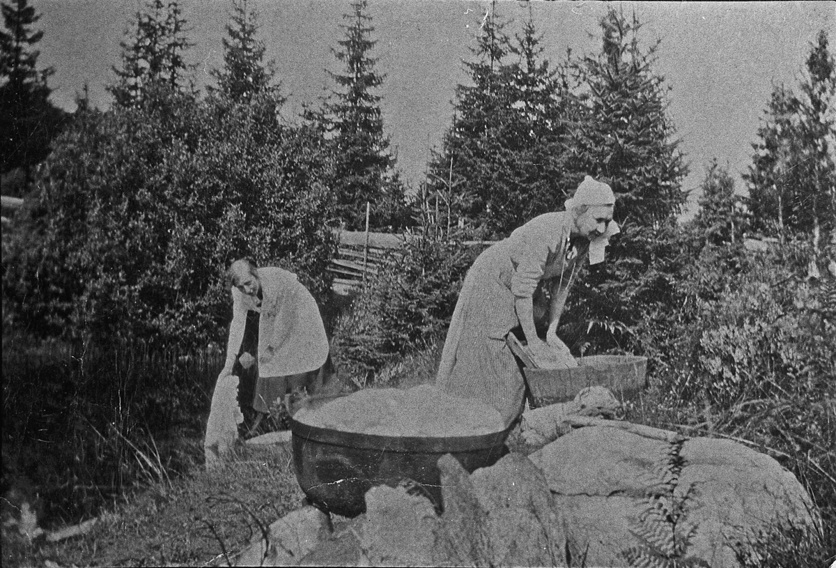 Kvinner som vasker klær ved en bekk. Ca. 1911. Bildet er fra en plass ved Holtteie mellom Granly og brua over Holtåa. Dette var en felles vaskeplass for husstandene omkring. Kvinnene er sannsynligvis vesle-Maren og hennes mor Maren Langbakken. (Eidsvoll i gamle glimt).