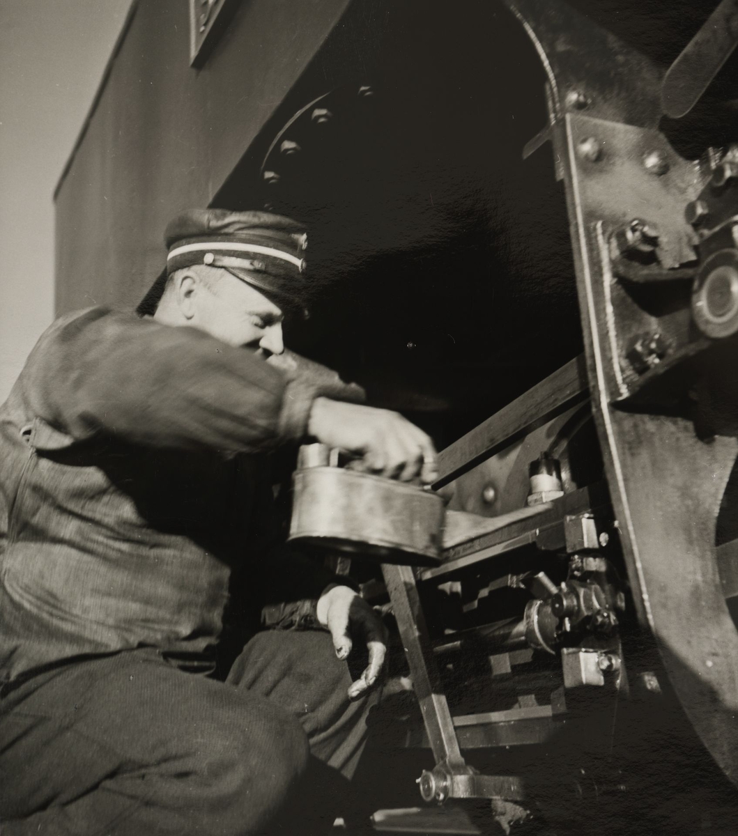 Lokomotivfører Syprian Aarstad smører gangtøyet på lokomotivet.