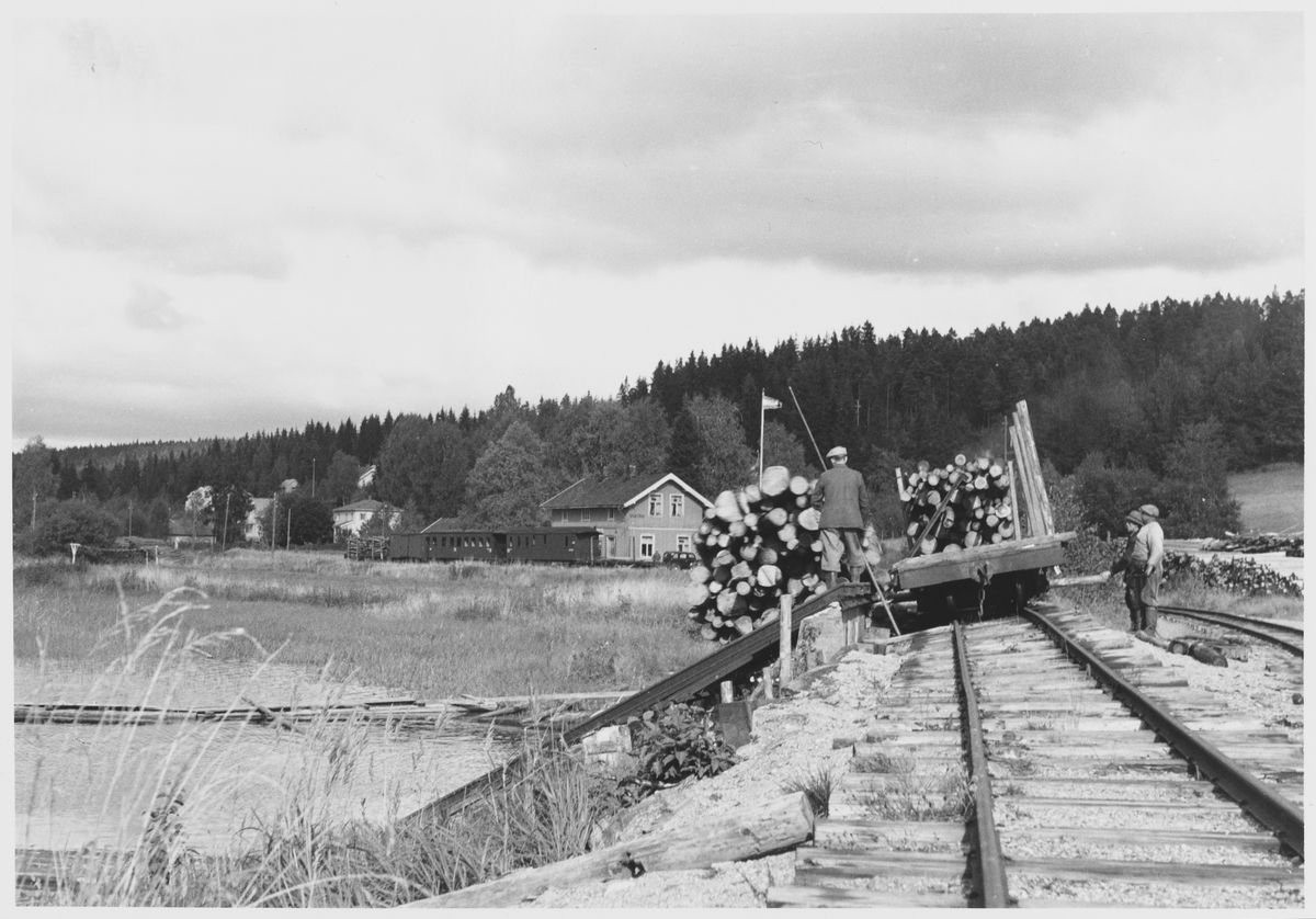 Tømmervelting fra jernbanevogn på Skulerud brygge. Sporet er jekket opp for at tømmerbunten lettere skal velte av vognen.