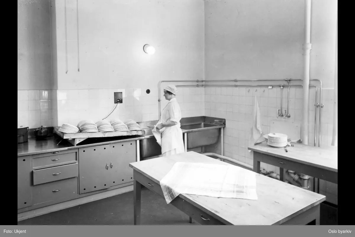 Kvinne som vasker opp, oppvask. Møllergatens skoles utvidelse, 1933 (albumtittel) (Møllergata skole)