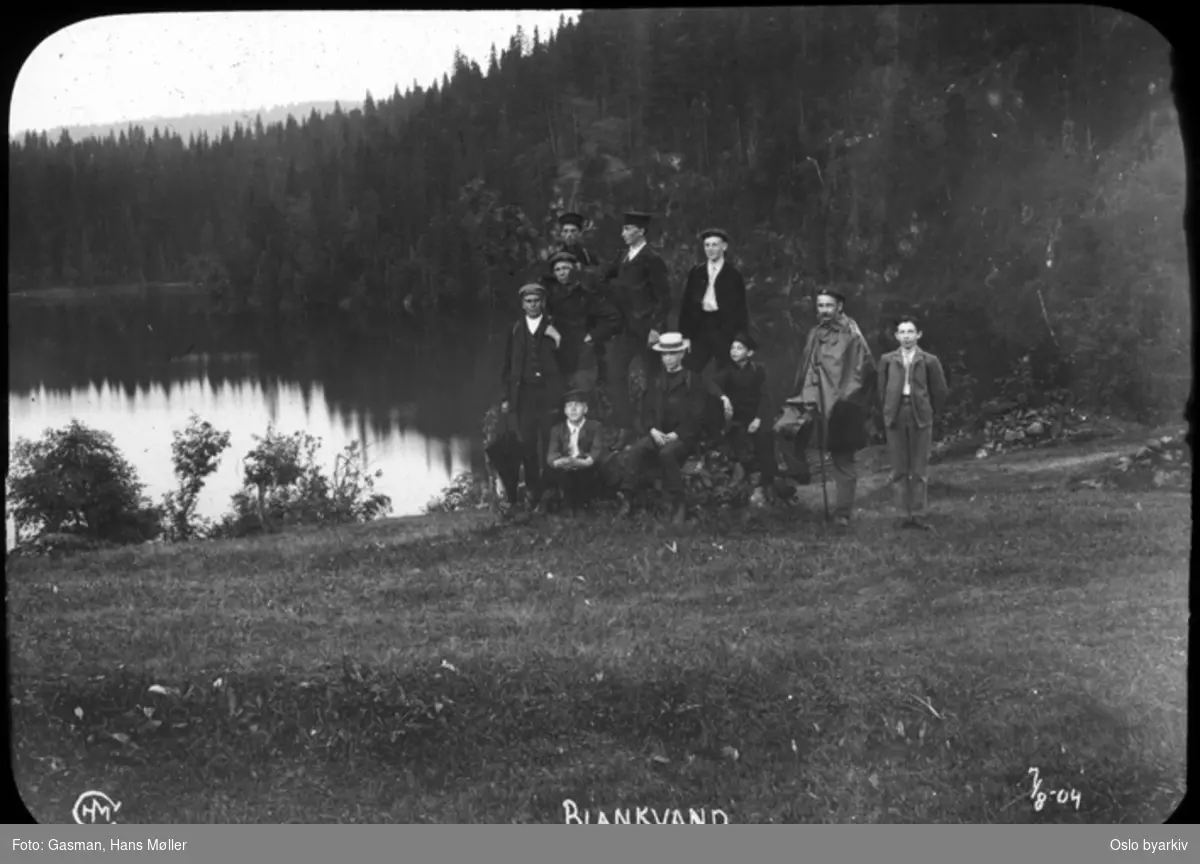 En gruppe menn poserer ved Blankvann i Nordmarka. En mann i speideruniform? (mannen med regnlaget)