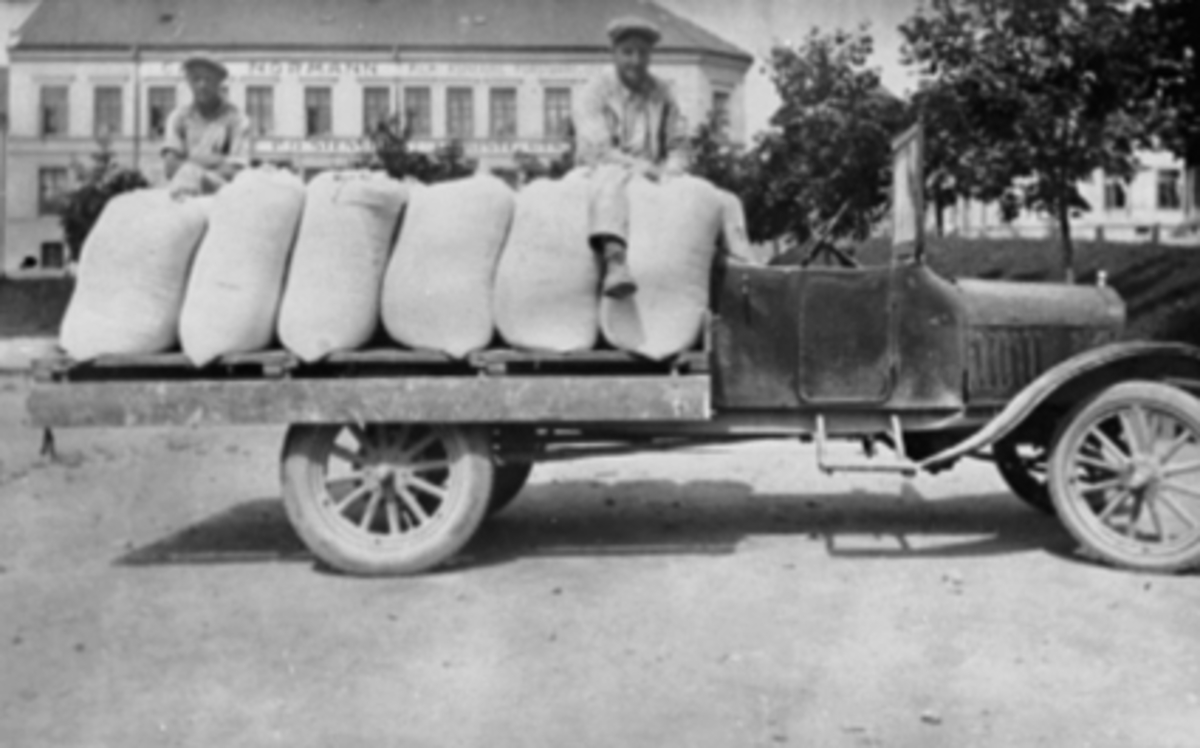 Ford TT 1917-27 lastebil, "Hagens Transport", Østre Torg, Hamar, varetransport, sekker på lasteplanet, to ukjente menn.