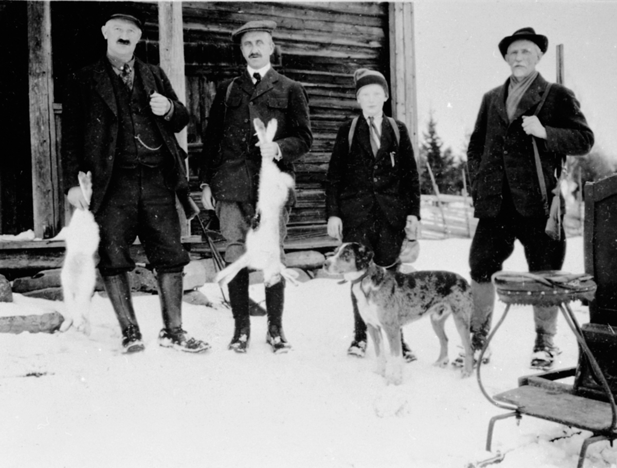 Gruppe jegere med gevær og hund, harejakt, Ødegården, sommerseter ved Opsal, Veldre, Ringsaker. Fra venstre er Anders Opsal, Olav Jørstad, Jørgen Opsal, Einar Narud.