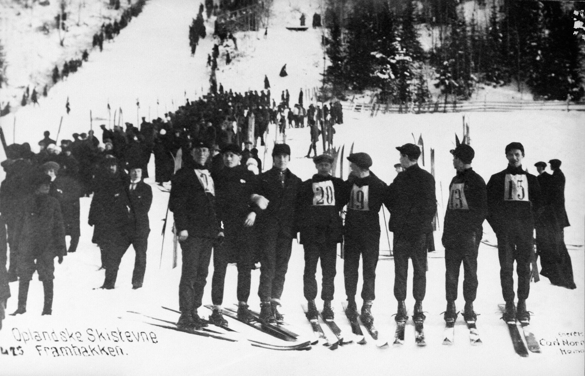 Postkort, Oplandske skistevne antatt 1917, Frambakken, Brumunddal. Gruppe skihoppere på sletta. Mange tilskuere.