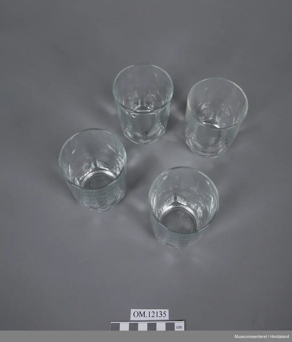 4 blanke drikkeglass på ein liten sokkel med ein krans av rundtslipt mønster på nederste tredjedel av glasset- mønsteret består av 6 ovale former.