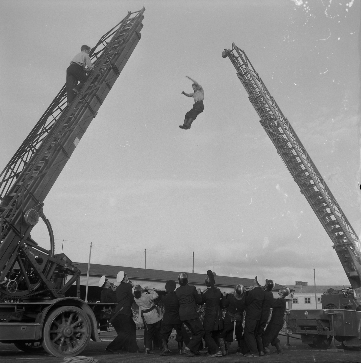Brannmannsdagen 1955. Oppvisning på Stadion. Brannmann hopper ned i brannseil