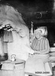 Kvinne koker kaffe på peisen mens hun leser avis