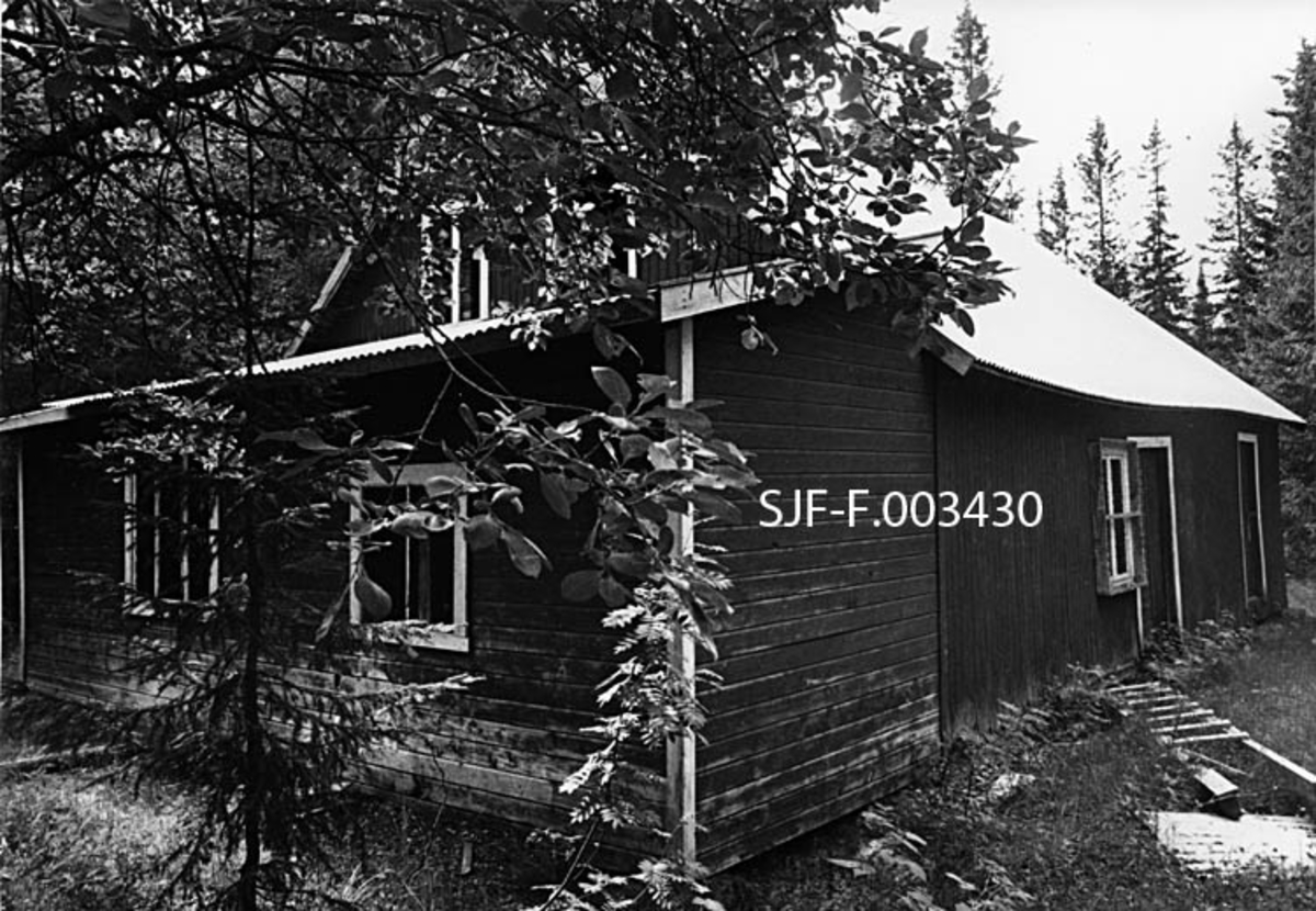 Klengstua i Målselv i Troms, fotografert i 1980.  Klengrommet var laftet, men det ytre bygningsskallet (som vi ser på dette fotografiet) later til å være utført i bordkledd bindingsverk.   Huset har en etasje, men et forholdsvis høyt, spissgavlet røste, som gav muligheter for et konglelager på loftet.  Bildet er tatt med vidvinkelobjektiv mot et av hjørnene på en gavl, der det var oppført et tilbygg, også utført i bordkledd bindingsverk med liggende panel, og med et pulttak som skrådde ut fra gavlen på hovedbygget.  Det tilbygde skuret hadde to vinduer, noe også gavlen på hovedhuset hadde.  Bildet viser også en av langveggene på sjølve klengstua, antakelig den langveggen som har vært betraktet som ”fronten” eller ”hovedfasaden” på huset.  Her er det ett vindu og to døråpninger, den ene med dobbelt port.  Da dette fotografiet ble tatt bar anlegget preg av et visst forfall.  Vindusgrindene i tilbygget var borte, og på marka foran huset lå det en defekt stige og ei bølgeblikkplate som hadde blåst av taket.  Eierne hadde tilsynelatende forsøkt å beskyttet anlegget mot hærverk ved å spikre ei ramme med netting foran vinduet på langveggen.  Skogen (selje, rogn, gran og furu) sto tett omkring bygningen. 