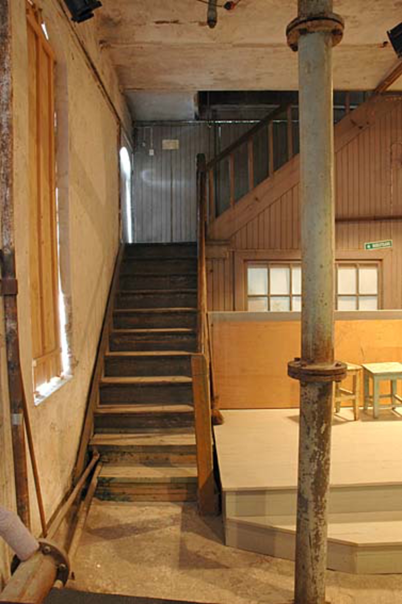 Interiør fra Klevfos Cellulose- & Papirfabrik i Løten i Hedmark, som siden 1986 har vært drevet som Klevfos industrimuseum.  Dette fotografiet er fra hollenderisalen.  Vi ser trappa opp mot limloftet i etasjen over, og vi ser de panelte treveggene og vinduet til formannskontoret.  Til venstre ser vi en teglmurt, pusset vegg der vindusåpningene var forblendet med trelemmer.  Vi skimter også et tak som var utført som kappehvelv av teglstein mellom stålskinner.  Til høyre i forgrunnen ser vi et vertikalt tilførselsrør til "supermølla".  Bak dette røret, foran formannskontoret, ser vi en platting som er innsatt som scene for teaterforestillingen «Arbesdaer», som siden 1988 har vært framført i dette lokalet fem-seks ganger hver sesong.  Forestillingen handler om dagliglivet i og omkring fabrikken. Ådalsbruk.