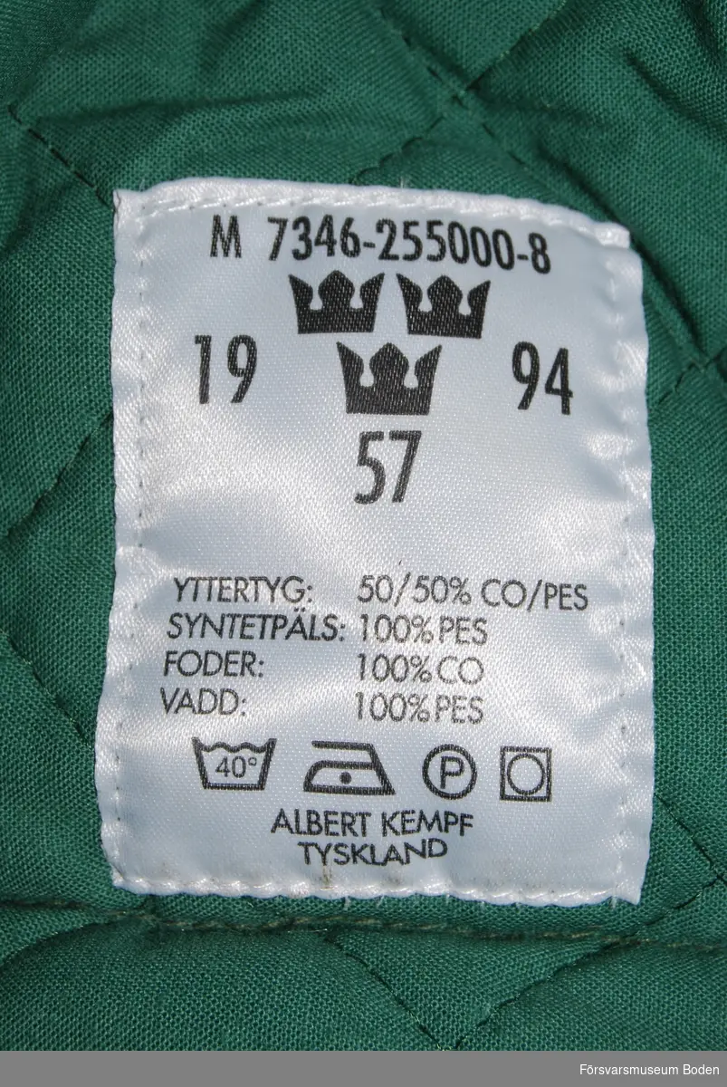 Olivgrönt tyg med mjuk skärm. Nerfällbara öronlappar, nacksskydd och invikbart pannskydd klädda med syntetpäls. Materielnr M7346-255000-8. Storlek 57. Tillverkad 1994 av Albert Kempf, Tyskland.