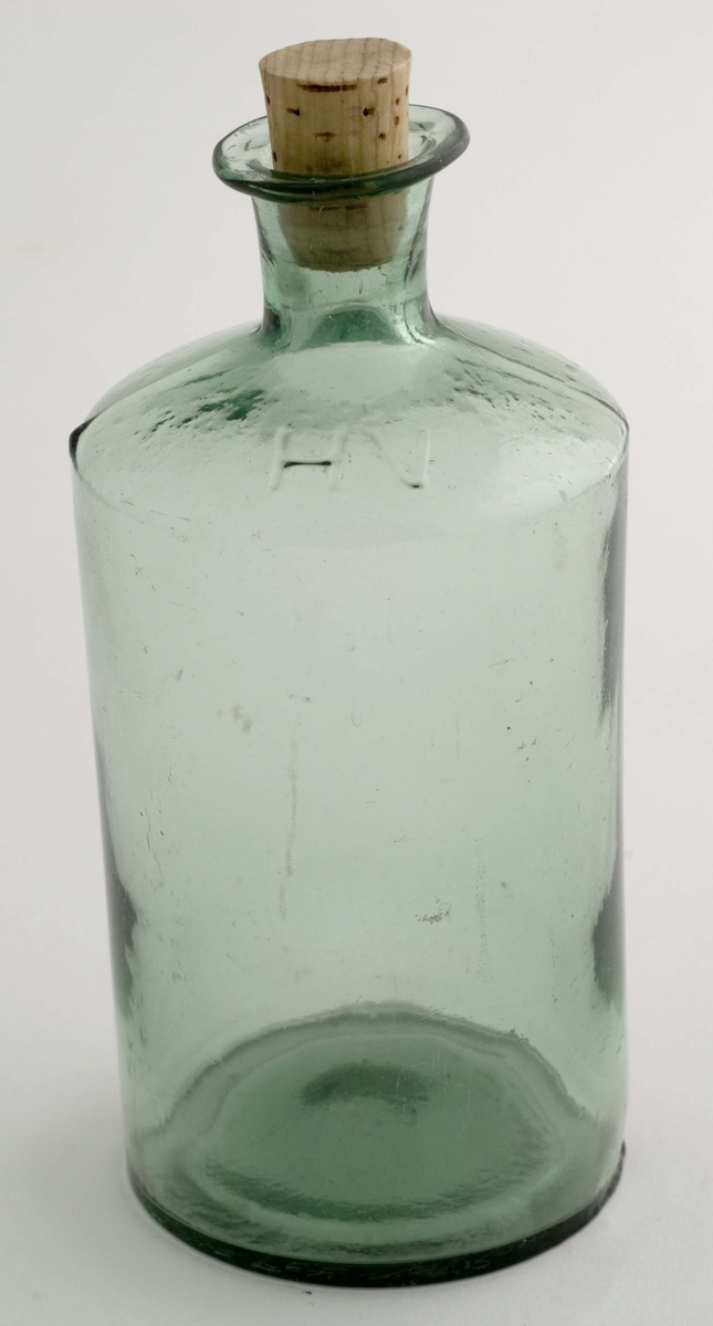 Medisinflaske med kork. Flaskens skulder er merket med bokstavene HV og tallet 16 støpt i glasset.