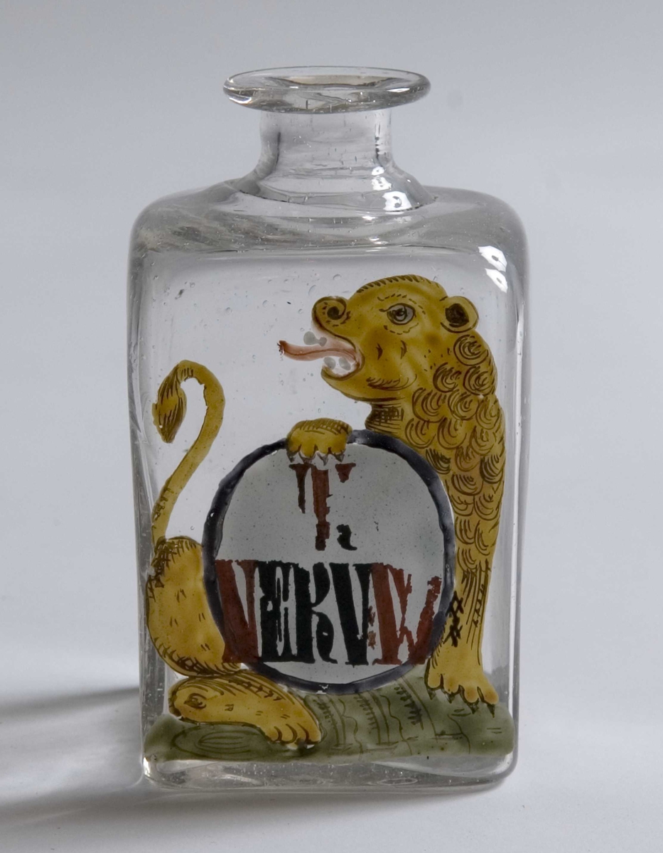 Firkantett glass med smal hals, hvit malt rund etikett. Sort skrift og sort kant.
Motiv: Løve som holder etikett