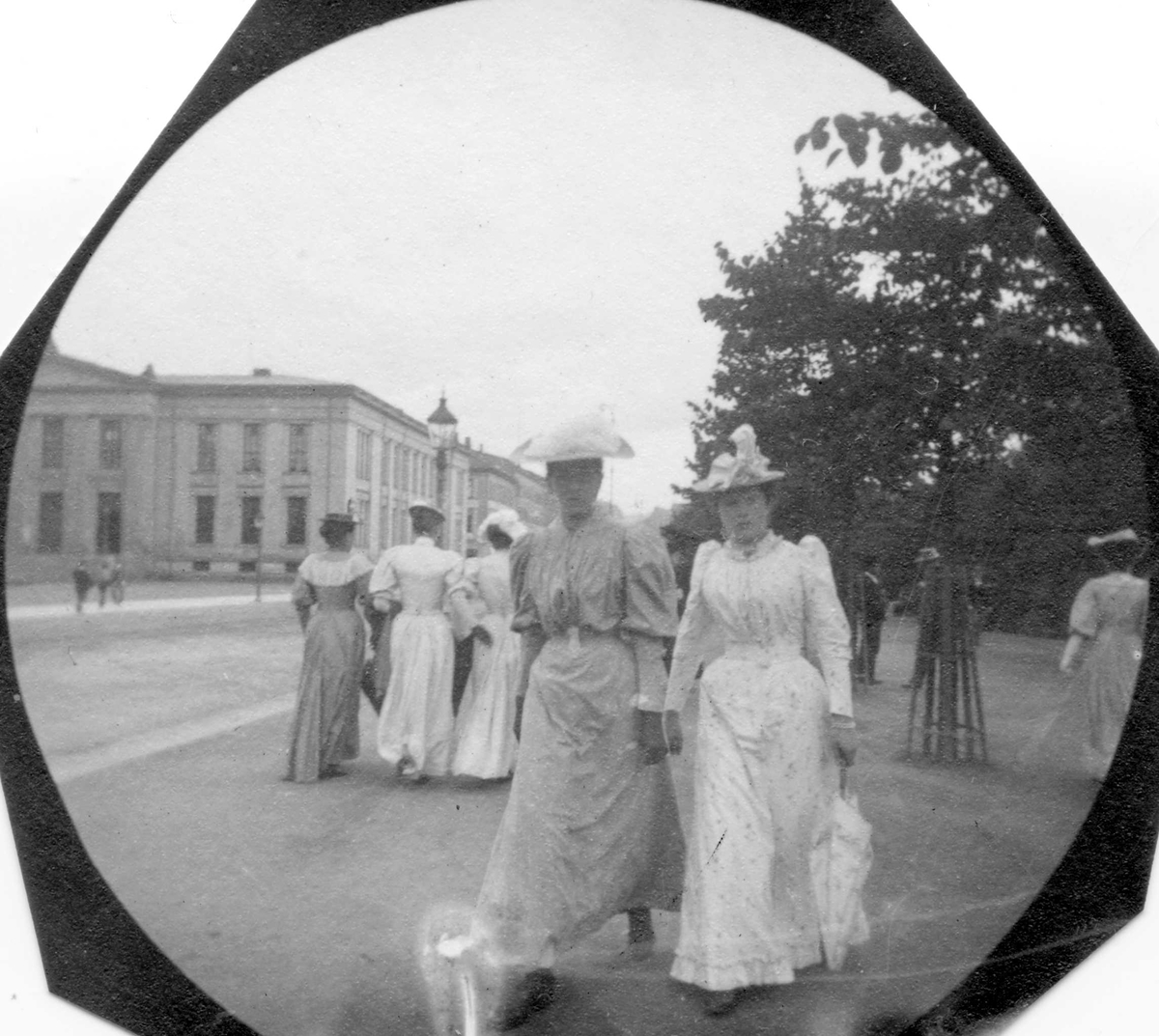 Kvinner spaserer i Studenterlunden, Karl Johans gate, Oslo,  med Universitetet i bakgrunnen.