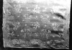 Hvit damaskserviett med strøblomster innrammet av rankeomsly