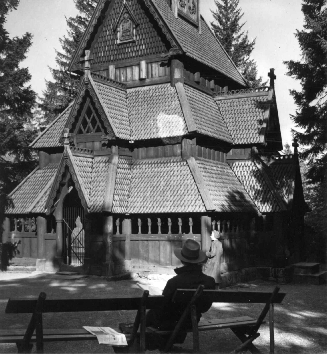 Stavkirken fra Gol i Hallingdal. Fotografert på Norsk folkemuseum (Oscar IIs samlinger), for magasinet Aktuell 1946. Stående foran kirken, til høyre: Kari Bjerke.