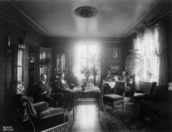 Holm. Stueinteriør. 1908-1910. To menn i en sofa. En mann og