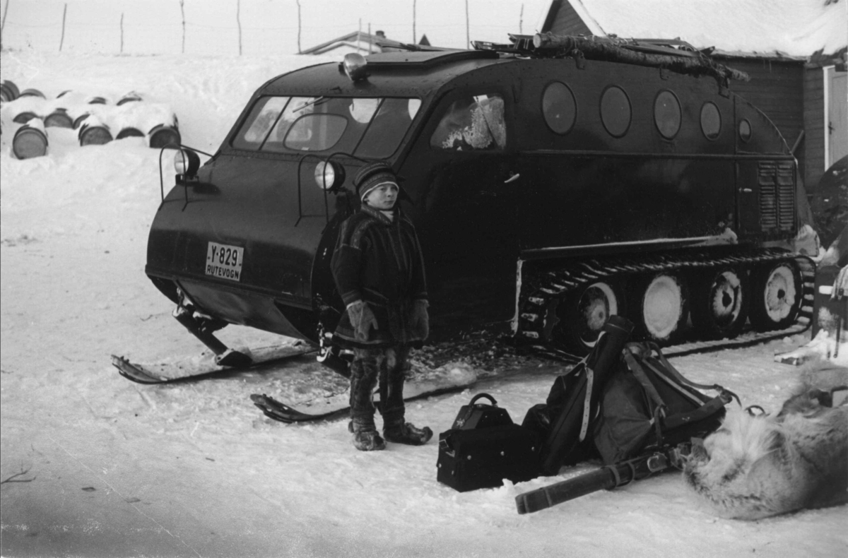 Snowmobil, snøbil. Utenfor står en gutt ved oppakkingen. Masi 1957.