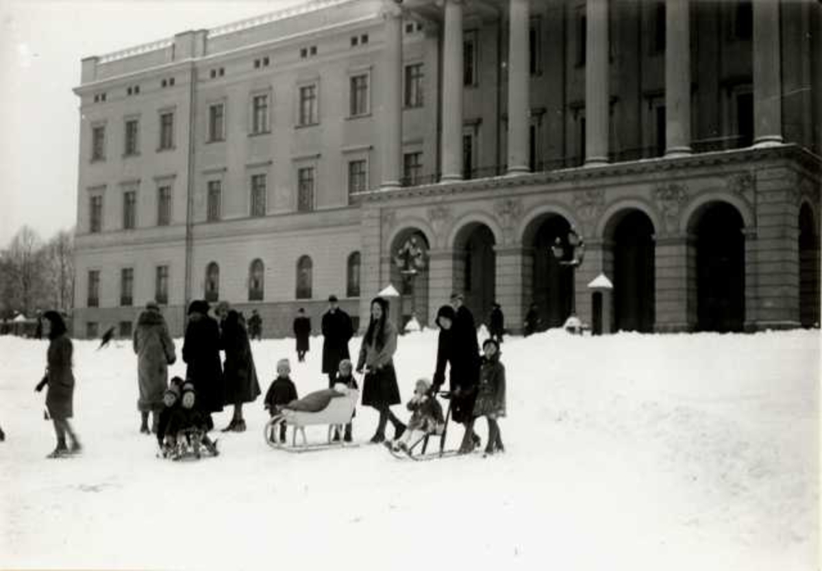Slottet, Oslo. 1930. Vinterbilde.  Kvinner og barn med sparkstøttinger på Slottsplassen.