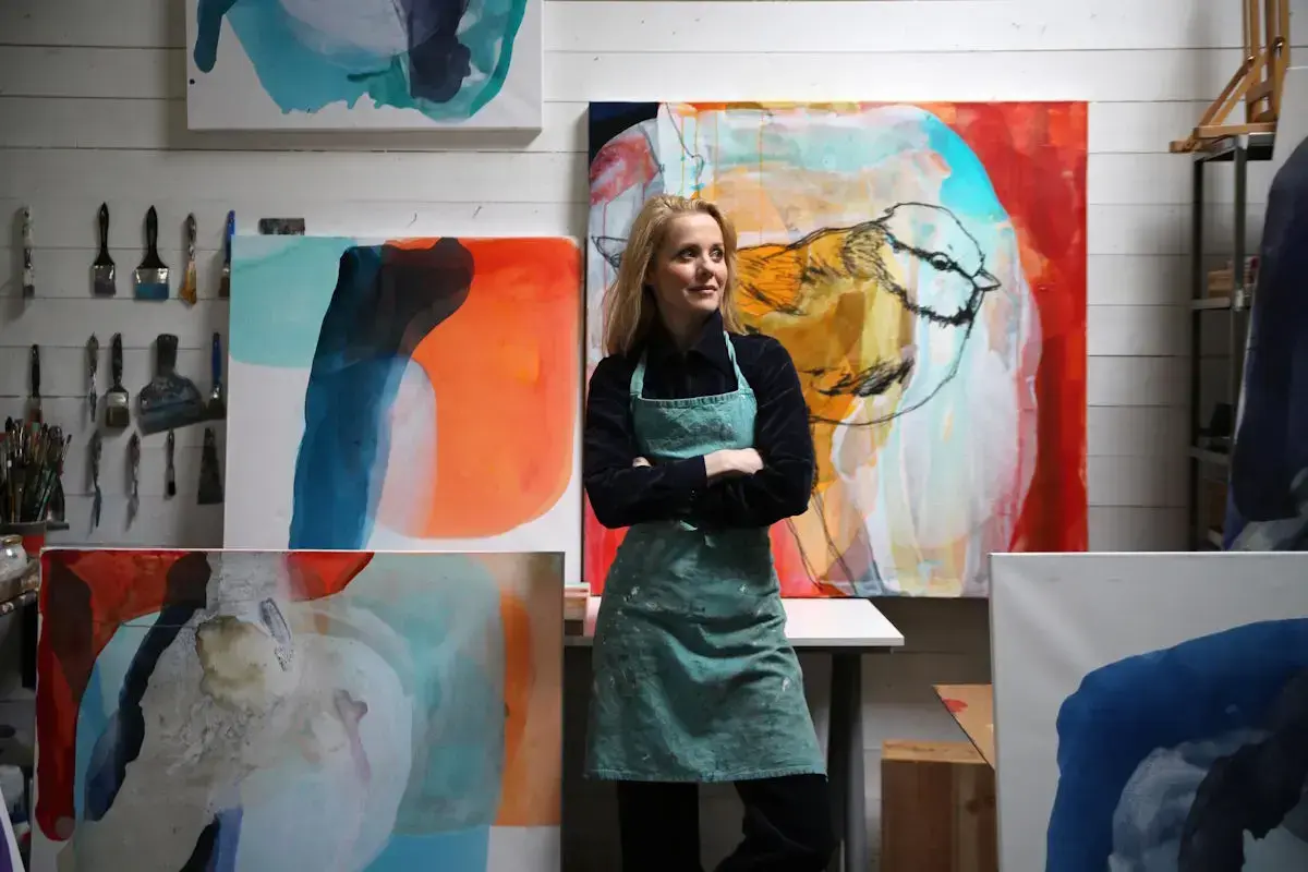 Gunilla Holm Platou ned forkle står framom fleire av sine eigne kunstverk