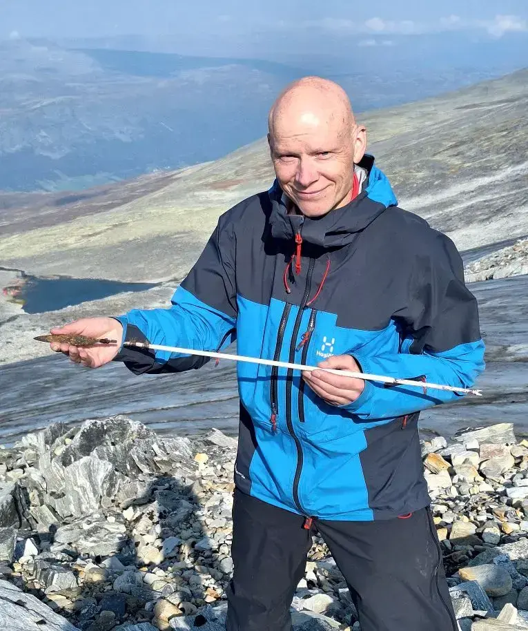 Mannlig arkeolog som holder en gammel pil og pilespiss